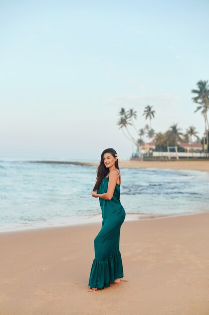 Portrait of beautiful young woman in dress on the beach. Pretty girl on tropical beach. Freedom concept, holiday, beach, sky background.