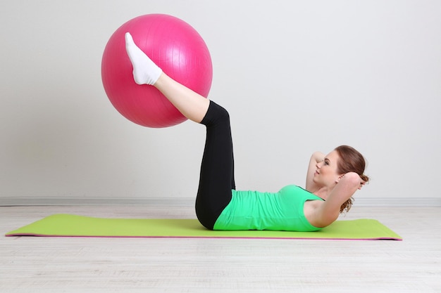 Portrait of beautiful young woman exercises with gym ball