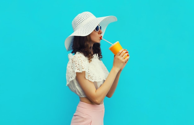 Portrait of beautiful young woman model with cup of coffee or fresh juice in white summer straw hat