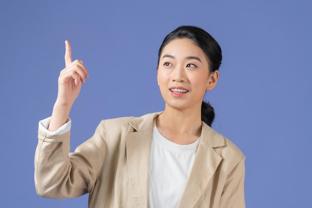 Portrait of beautiful young woman pointing up over purple background