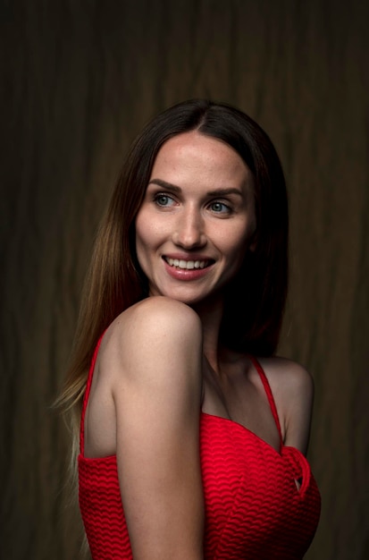 portrait of a beautiful young woman in a red dress studio shot on a dark background