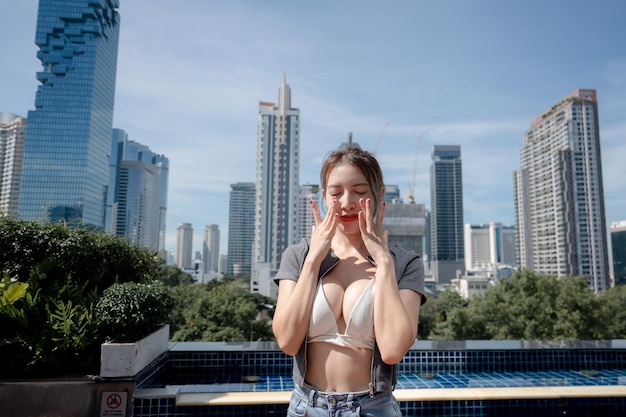 Portrait of beautiful young woman relaxing with city view wearing white bikini and long leg jeans