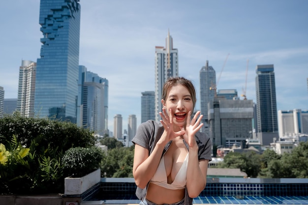 Portrait of beautiful young woman relaxing with city view wearing white bikini and long leg jeans