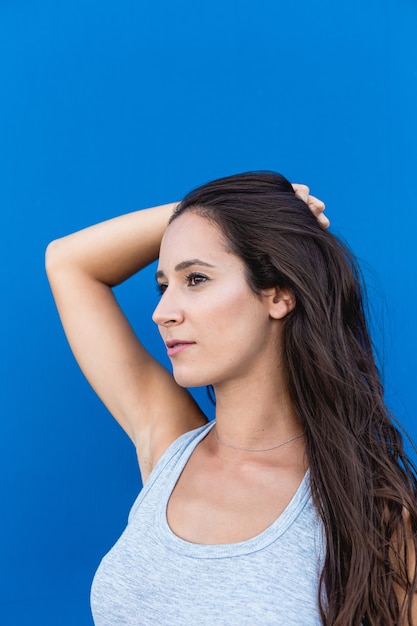 Portrait of a beautiful young woman smiling and posing with a blue wall in the background