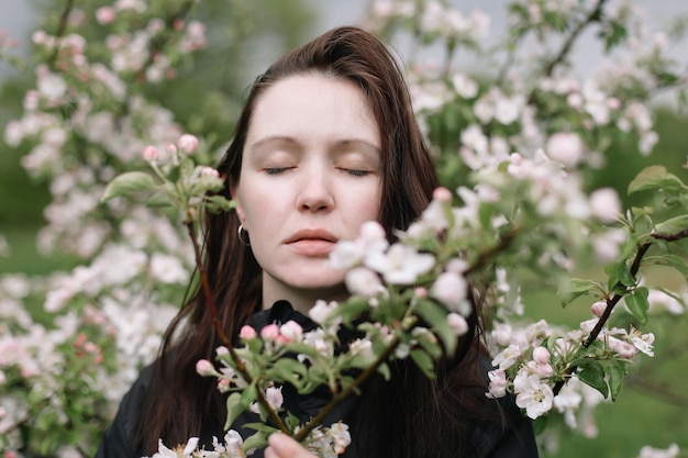 Portrait of a beautiful young woman in the spring garden among apple blossom