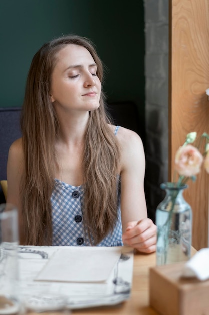 Portrait of beautiful young woman in summer sundress in a restaurant Girl with closed eyes enjoys wonderful day at table in cafe