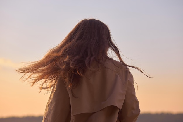 Portrait of a beautiful young woman at sunset Natural beauty long hair woman in a raincoat