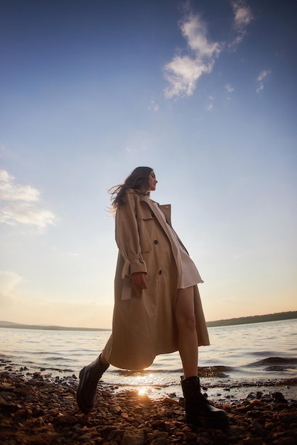 Portrait of a beautiful young woman at sunset Natural beauty long hair woman in a raincoat