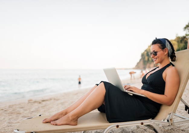 Portrait of a beautiful young woman using laptop on the beach. 