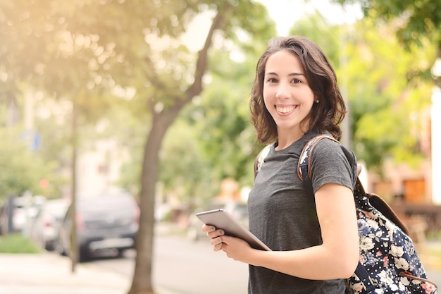 Portrait of beautiful young woman using tablet outdoors.