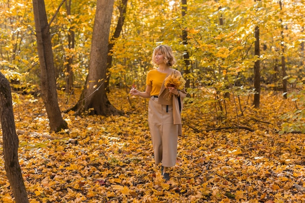 Portrait of beautiful young woman walking outdoors in autumn nature. Fall season and stylish girl concept.