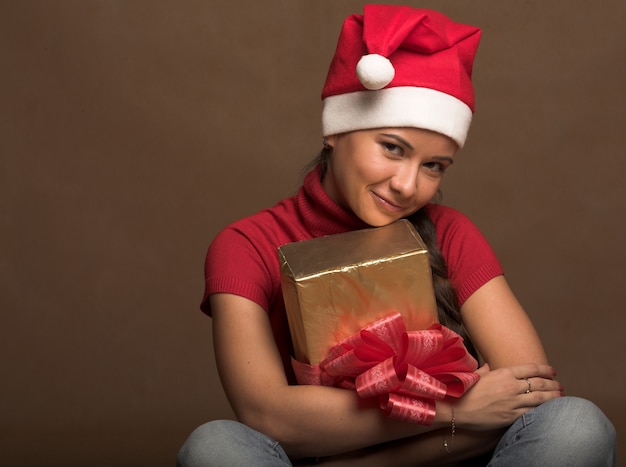 Portrait of beautiful young woman wearing santa claus hat with present