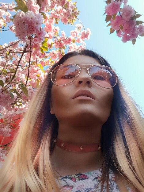 Portrait of beautiful young woman wearing sunglasses against sky