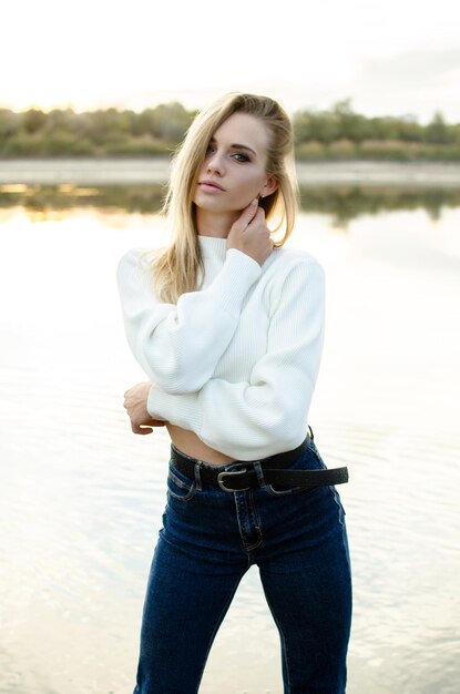 Portrait of a beautiful young woman in white sweater outdoors