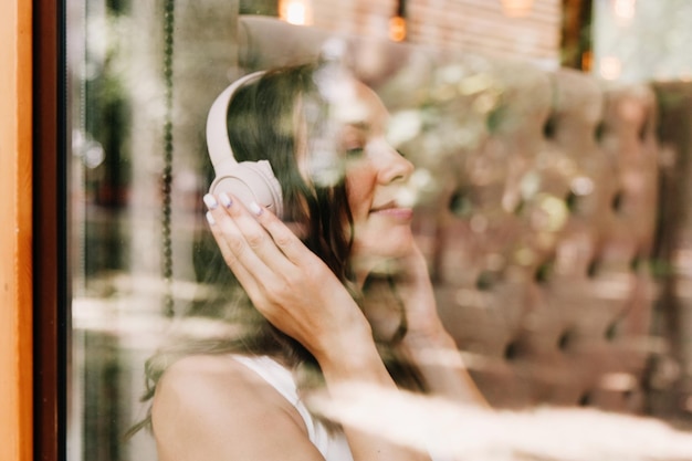 Portrait of a beautiful young woman with headphones who listens to music while sitting in a street cafeEnjoy the music generation Z