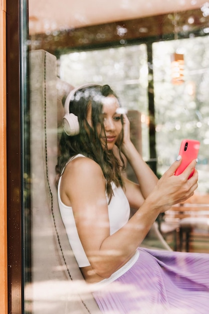 Portrait of a beautiful young woman with headphones who listens to music while sitting in a street cafeEnjoy the music generation Z