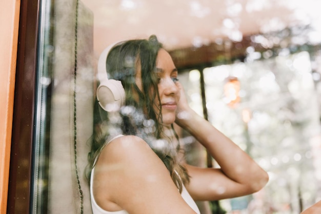 Portrait of a beautiful young woman with headphones who listens to music while sitting in a street cafeEnjoy the music generation Z