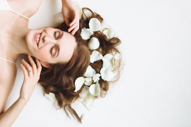 Portrait of beautiful young woman with white rose petal on white background. Relax and spa