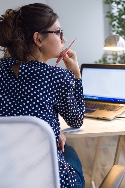 Portrait of beautiful young woman working with laptop in her office.