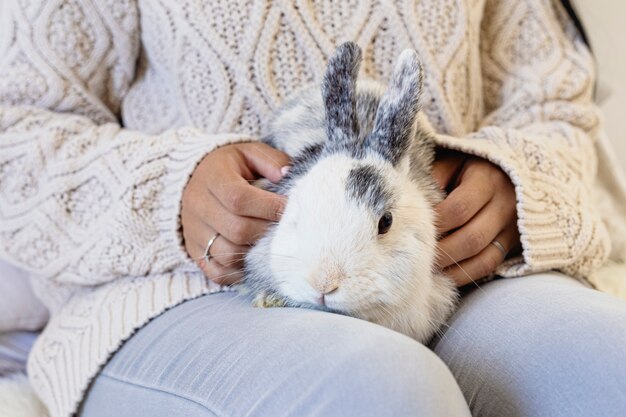 Photo portrait of a beautiful young womman petting a rabbit