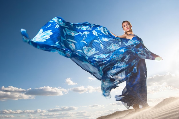 Portrait of a beauty woman in blue dress on the desert