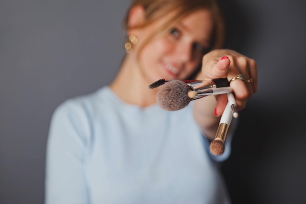 Portrait of beauty young blonde with makeup brushes