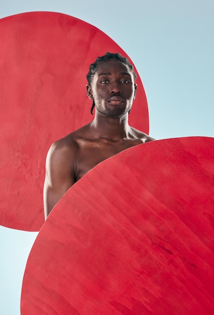 Portrait black man and muscle with creativity fitness and artistic on a blue studio background Face African person and model with red circle art and exercise with aesthetic proud and mockup