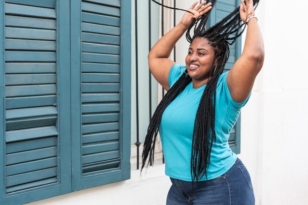 Portrait of a black woman in a blue blouse holding her braids