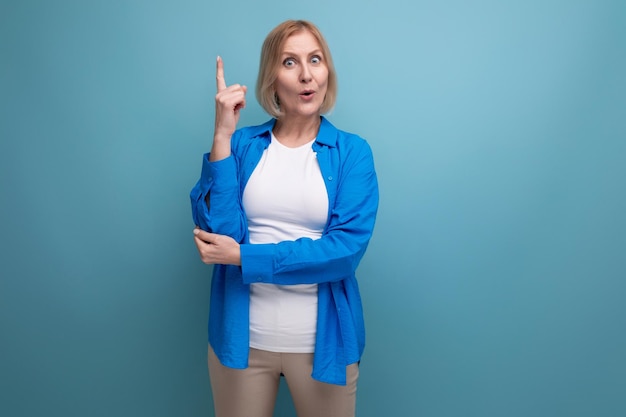 Portrait of a blond attractive middleaged woman in a casual stylish shirt on a blue background with