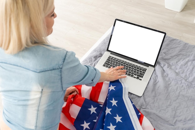 Portrait of a blond girl with USA flag with laptop.