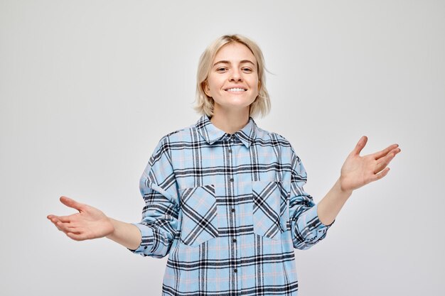 Portrait blond young woman happy face smiling joyfully with raised palms and shocked open mouth isolated on white studio background