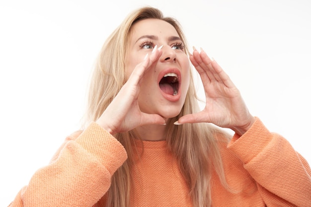 Portrait of blond young woman screaming into her palms on white studio background Important information news conceptxA