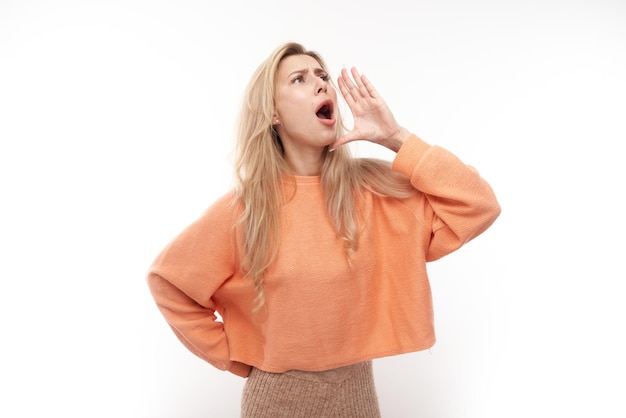 Portrait of blond young woman screaming into her palms on white studio background Important information news conceptxA