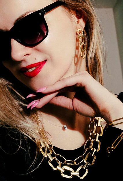 Portrait of a blonde in a black dress sunglasses and with red lipstick on her lips