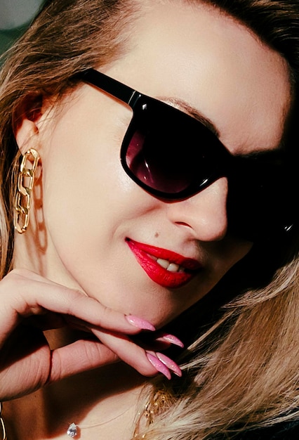 Portrait of a blonde in a black dress sunglasses and with red lipstick on her lips