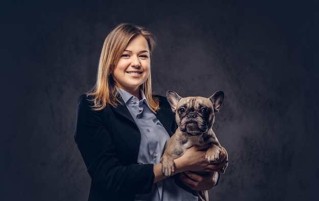 Portrait of a blonde business woman in a formal suit holds a cute dog