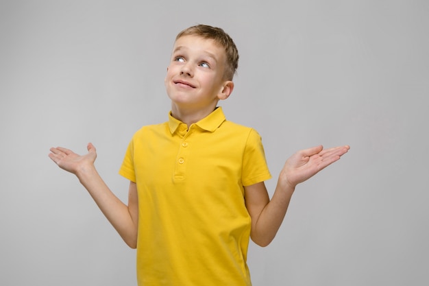 Portrait of blonde caucasian little boy in yellow t-shirt with open arms