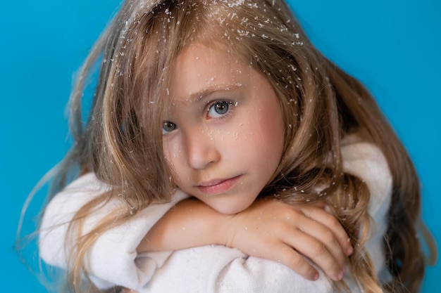 portrait of a blonde girl in a winter knitted hat. artificial snow in the studio