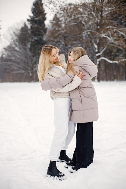 Portrait of blonde mother and teen daughter standing in winter forest