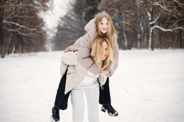 Portrait of blonde mother and teen daughter standing in winter forest