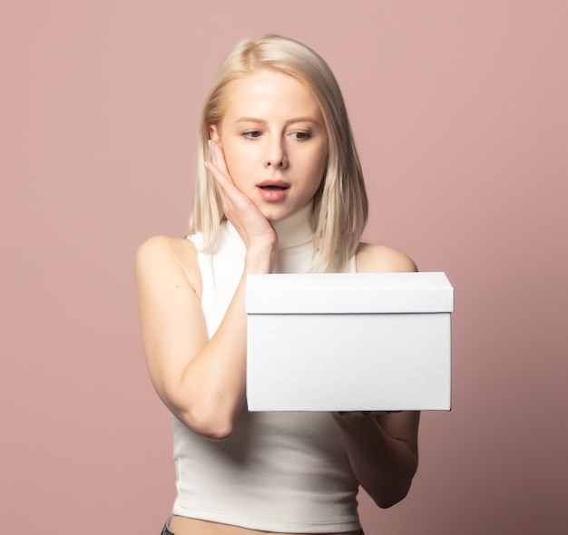 Portrait of blonde in top with white gift box on pink