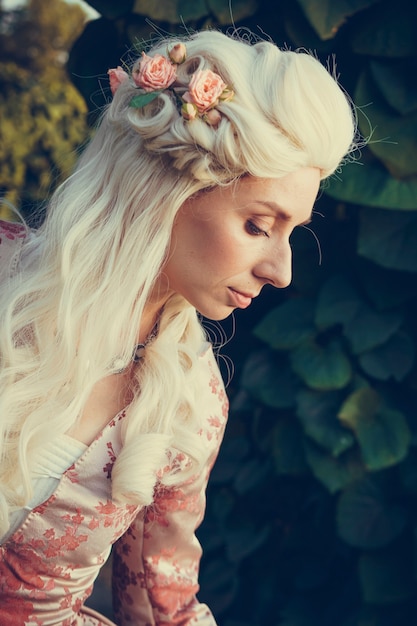 Portrait of blonde woman dressed in historical Baroque clothes with old fashion hairstyle, outdoors. Luxurious medieval dress