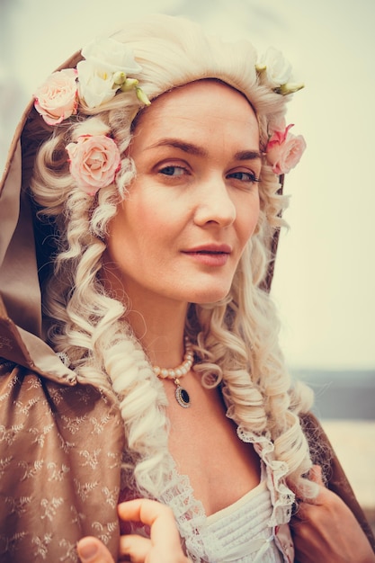 Portrait of blonde woman dressed in historical Baroque clothes with old fashion hairstyle