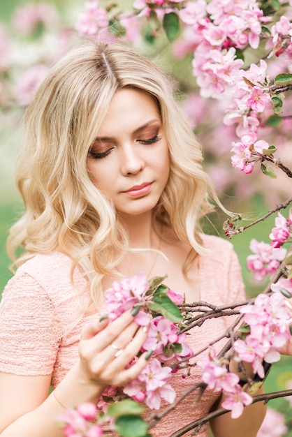 Portrait of a blonde woman in pink flowers. Spring garden