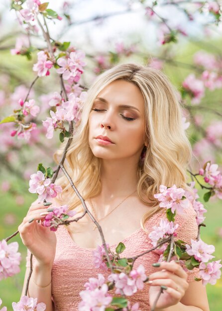 Portrait of a blonde woman in pink flowers. Spring garden