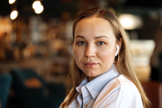 Portrait of a blonde woman in white shirt sitting in cafe