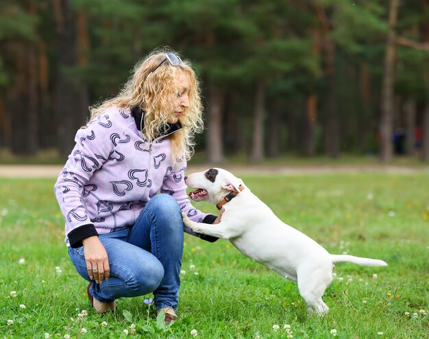 Portrait of a blonde woman with a dog in the park