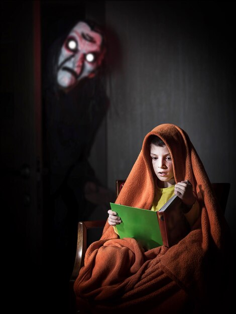 Portrait of a boy reading a book of spooky stories