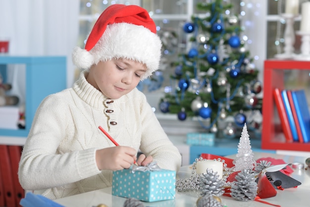 Portrait of boy in Santa hat writing letter