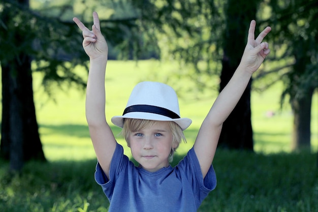 Portrait of boy showing victory hand sign on nature background